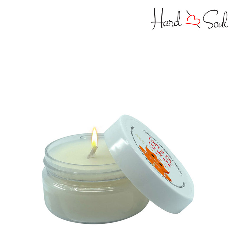 White Jar of Naughty Massage Candle Lick My Icing 1.7oz with the lid partially off, showing the candle lit inside - HardnSoul