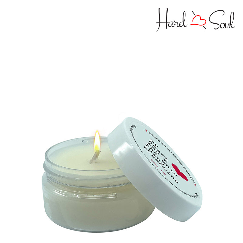 White Jar of Naughty Massage Candle Throbbing Heart 1.7oz with the lid partially off, showing the candle lit inside - HardnSoul