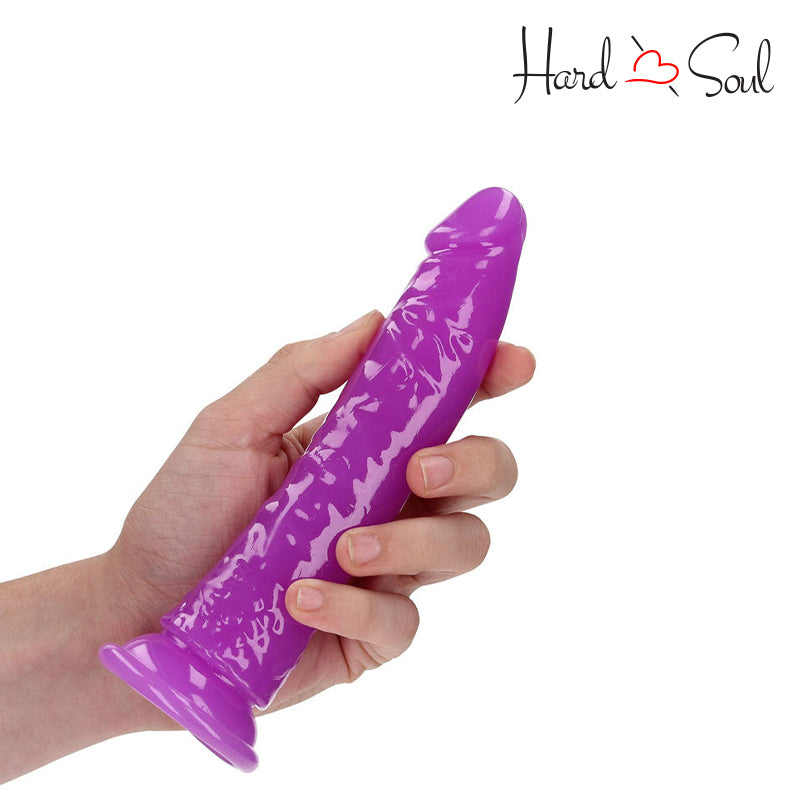 A RealRock Glow in the Dark 7 Inch Slim Dildo Purple in a hand - HardnSoul