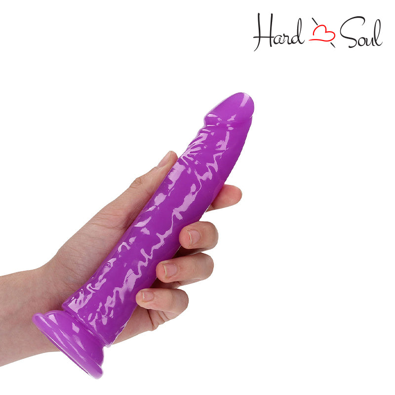 RealRock Glow in the Dark 8 Inch Slim Dildo Purple in a hand - HardnSoul